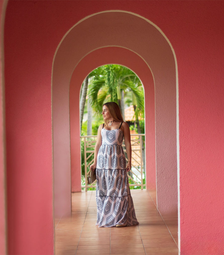 Elegantly dressed woman in a long, arched hallway.