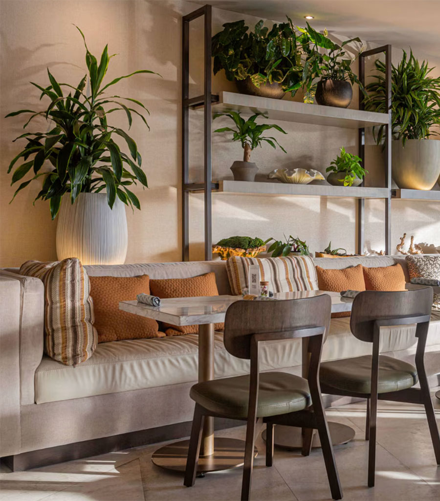 JW Marriott Panama Restaurant featuring a long bench style seating with accent pillows and sage green chairs separated by the dining tables.