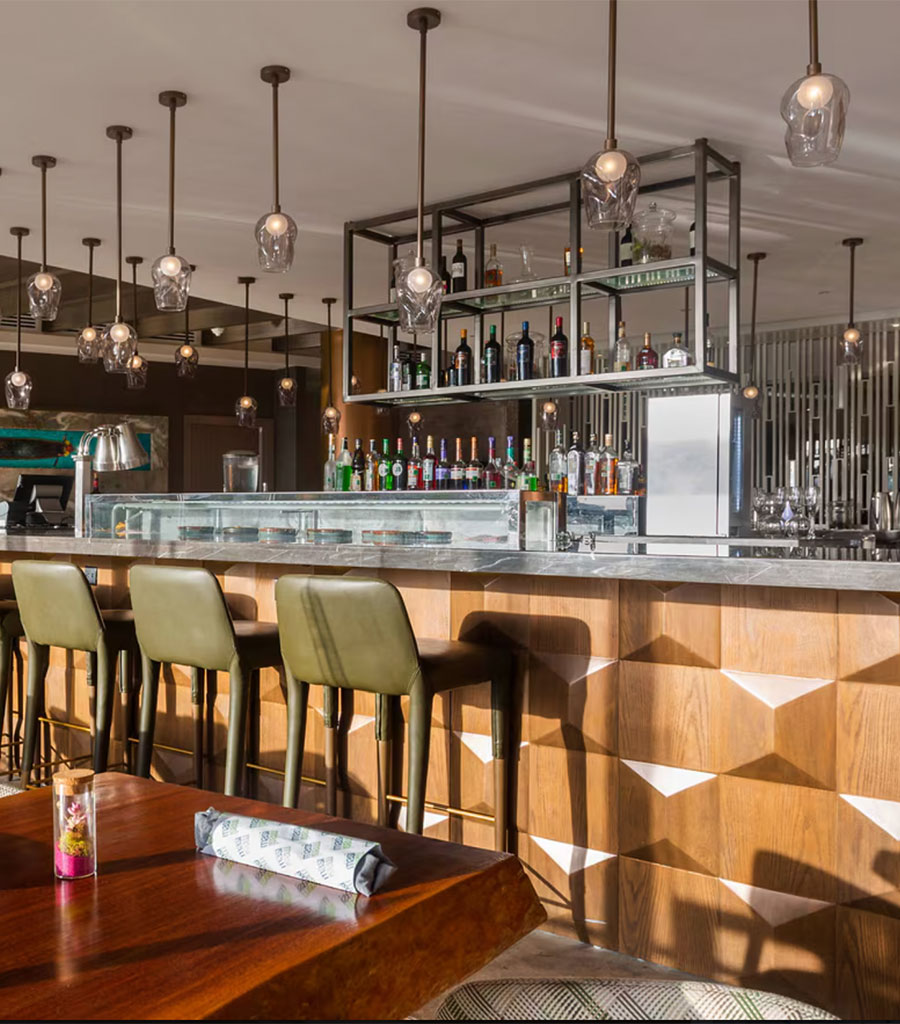JW Marriott Panama Bar featuring sage green bar stools and hanging pendant lights.
