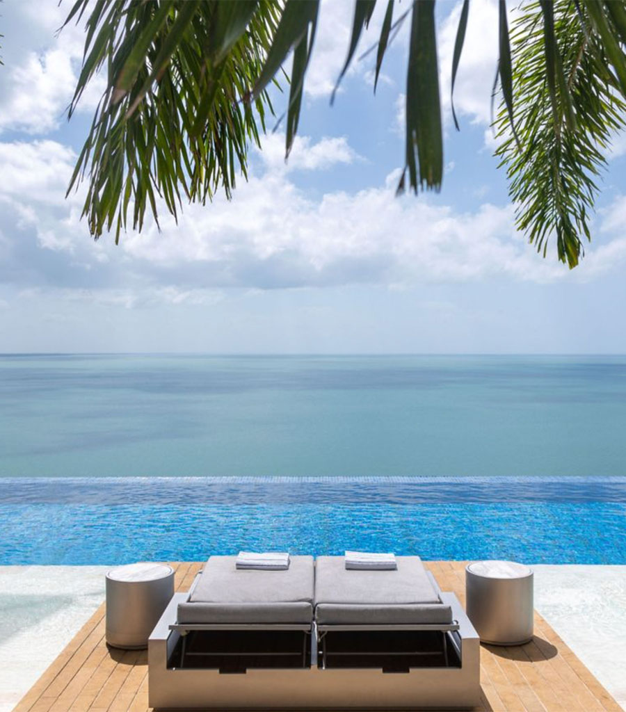 JW Marriott Panama Pool Area feturing two pool loungers placed in front an an infinity pool with the ocean beyond.