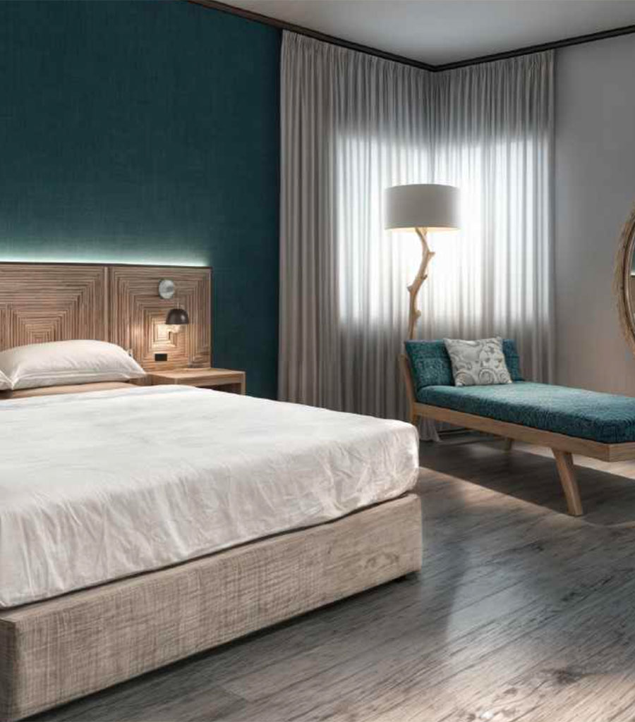 Marseilles Hotel Guest Room featuring a king sized bed with white linens and a teal patterned day lounger.