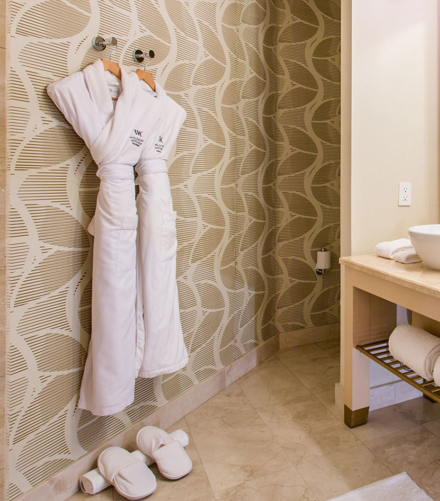 Waldorf Astoria Guest Bath featuring white logoed bathrobes.